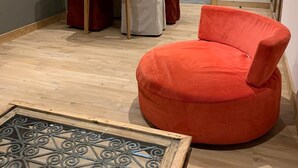 Un área de comedor con una silla roja redondeada, una mesa blanca y dos sillas rojas.