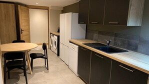 Una cocina compacta con armarios oscuros, un refrigerador blanco, un lavamanos y una lavadora.