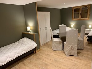 A small, well-lit room with a bed, a desk, and two chairs. There is a wardrobe and a window with wooden frames. - Appartement Duplex 190m² à Courchevel Village 1550 (Courchevel)