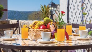A table set with fruits, a teapot, and glasses of orange juice, with a view of the mountains in the background. - Lovely home in Grizane (Grizane)