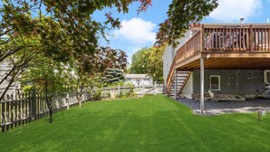 Ein gepflegter Rasen mit einer Holzterrasse und einem weißen Zaun.