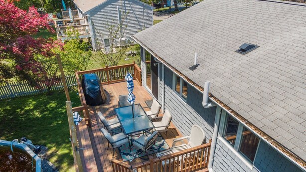 Eine Terrasse mit Gartenmöbeln, einem Grill und einem überdachten Bereich.