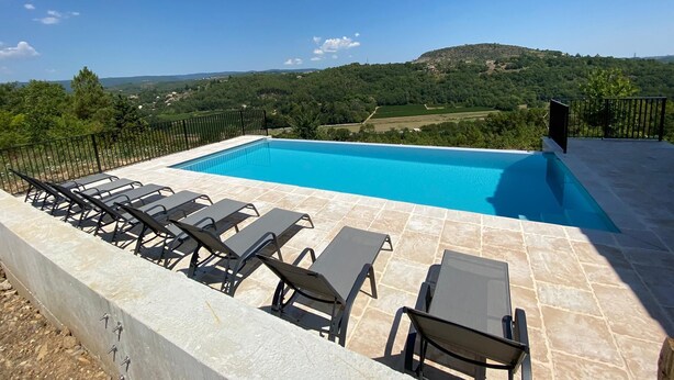 A swimming pool with lounge chairs and a scenic view of hills. - La Cigale, beautiful villa with infinity pool and breathtaking views  (Chassagnes)