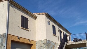A two-story building with a stone facade, a wooden garage door, and a balcony with a metal railing. - La Cigale, beautiful villa with infinity pool and breathtaking views  (Chassagnes)
