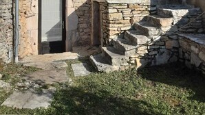 Uma casa de pedra com telhado de telhas, porta de madeira e um pequeno lance de escadas que dá acesso à entrada.