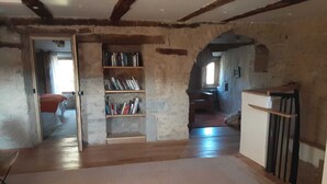 Quarto rústico com paredes de tijolos aparentes, uma estante de madeira e um amplo espaço aberto.