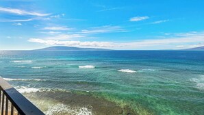 Une vue dégagée sur l’océan, avec des vagues, une montagne lointaine et un ciel clair.