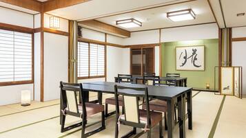 A traditional Japanese-style room with tatami flooring, a low table with chairs, and shoji screens.