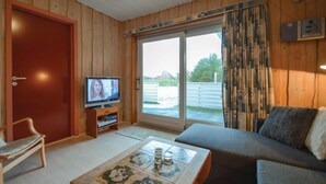 A cozy living room with a television, a sofa, a coffee table, and a door leading to a balcony.