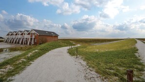 A building with multiple rooms, a gravel path, and a grassy field.