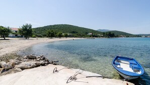 Una playa con agua cristalina, un bote y un litoral rocoso.