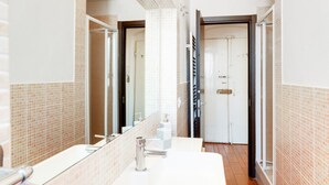 A modern bathroom with a large mirror, a white sink, and a shower area.