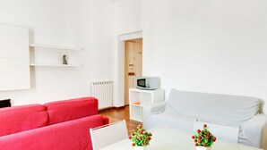 A modern living room with a red sofa, a white sofa, and a small table with decorative items.