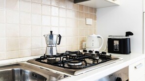A kitchen with a gas stove, a coffee maker, a kettle, and a toaster.