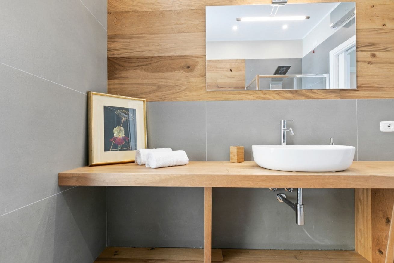 A modern bathroom with a wooden vanity, a white sink, and a framed picture on the wall.