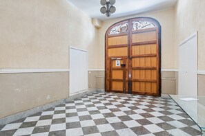 Een geruite vloer, een houten deur met een metalen decor en een witte muur.