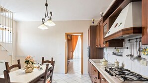 A kitchen with a gas stove, wooden cabinets, and a dining area with a table and chairs.