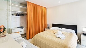 A hotel room with a bed, a bedside table, a nightstand, a wardrobe, and a mirror.