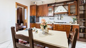 A kitchen with wooden cabinets, a dining table with chairs, and a vase of flowers.