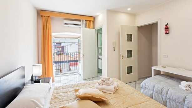 A hotel room with two beds, a balcony, and a bathroom.