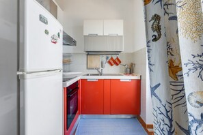 A compact kitchen with white and red cabinets, a built-in oven, and a small countertop.