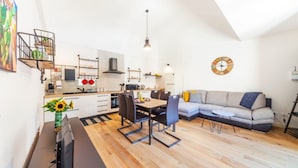 A modern kitchen with a dining area, a sofa, and a clock on the wall. - Valuk-Piazza Duomo Charming Apartment (Syracuse)