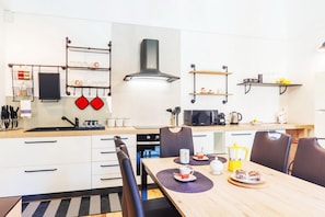 A modern kitchen with white cabinets, a black stove, and a dining area with a wooden table and chairs.