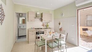 Una cucina compatta con zona pranzo, un orologio ben visibile e un piccolo tavolo con sedie.