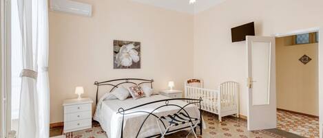 Une chambre à coucher avec un lit, des tables de chevet, un berceau et un lustre.