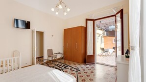 Una camera da letto con un letto, un armadio in legno, una televisione, una sedia e un tavolo.
