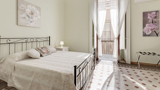 Una camera da letto con un letto, un comodino, una finestra con tende e vista all'esterno.