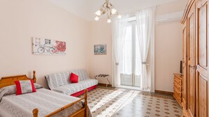 Una camera da letto con due letti, un armadio in legno, un lampadario e una finestra con tende.
