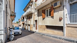 Een smalle straat met kinderkopjes, omzoomd door gebouwen, waarvan sommige balkons en airconditioners hebben.