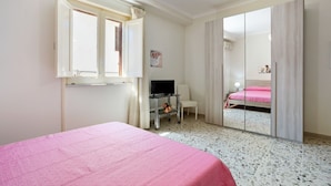 Een slaapkamer met een bed, een televisie, een bureau en een spiegel.