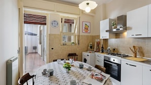 Een moderne keuken met witte kasten, een gasfornuis en een eethoek met een ronde tafel voor vier personen.