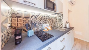 Une cuisine moderne avec un crédence décorée, un four à micro-ondes encastré, une bouilloire et un radiateur portatif.