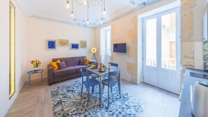 Un salon moderne comprenant un canapé, une table à manger et des chaises, un lustre et un tapis à motifs.