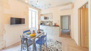 Une cuisine moderne équipée d’un téléviseur à écran plat, d’une table à manger avec des chaises et d’un tapis à motifs.