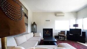 Una sala de estar con sofá, chimenea, televisor y un ventanal grande.