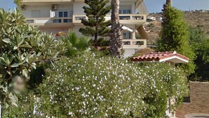 Un edificio de varios pisos con balcones, rodeado de exuberante vegetación y plantas en flor.