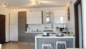 Una cocina moderna con armarios blancos, una isla central con taburetes, un microondas y una estufa.
