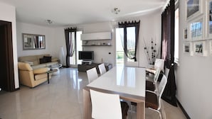 Una sala de estar moderna con un sofá, televisor y comedor con sillas y una mesa.