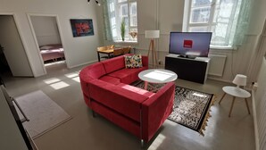A modern living room with a red sectional sofa, a small round table, a television, and a patterned rug.
