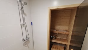 A shower area with a metal hose, a blue-handled mop, and wooden shelves.