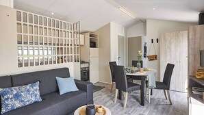 Een moderne woonkamer met een bank, stoelen, een eettafel en een keukenhoek.
