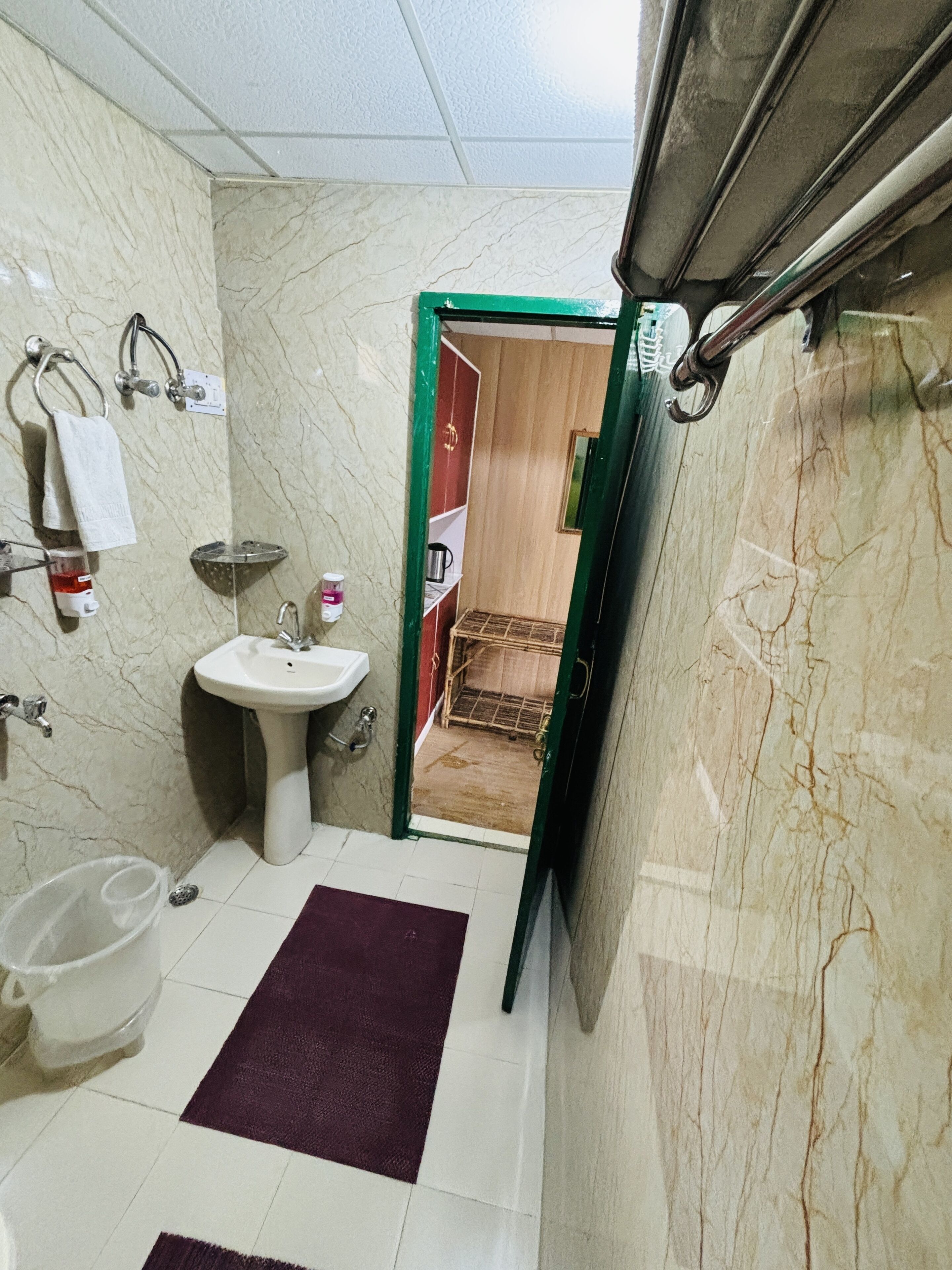Een badkamer met een wastafel, spiegel, handdoekrek en douche.