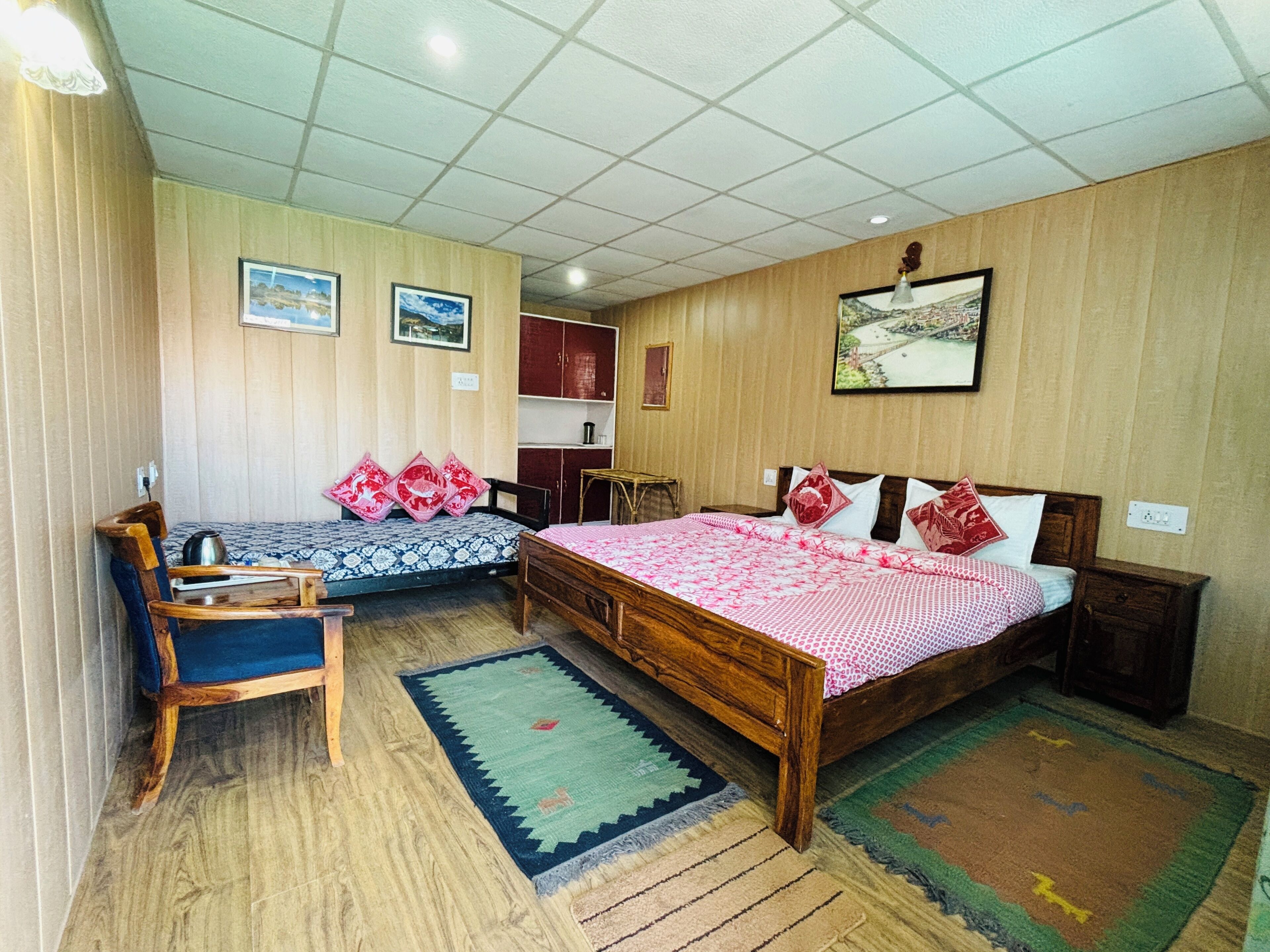 A room with two beds, a wooden desk, and a chair.