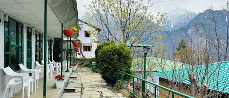 Un hôtel avec un chemin pavé de pierres menant à des chaises en plastique blanches et à des plantes en pot.