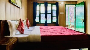A bedroom with a bed, a window with curtains, a green door, and a painting on the wall. - Himalayan High, Auli, By Himalayan Eco Lodges (Joshimath)