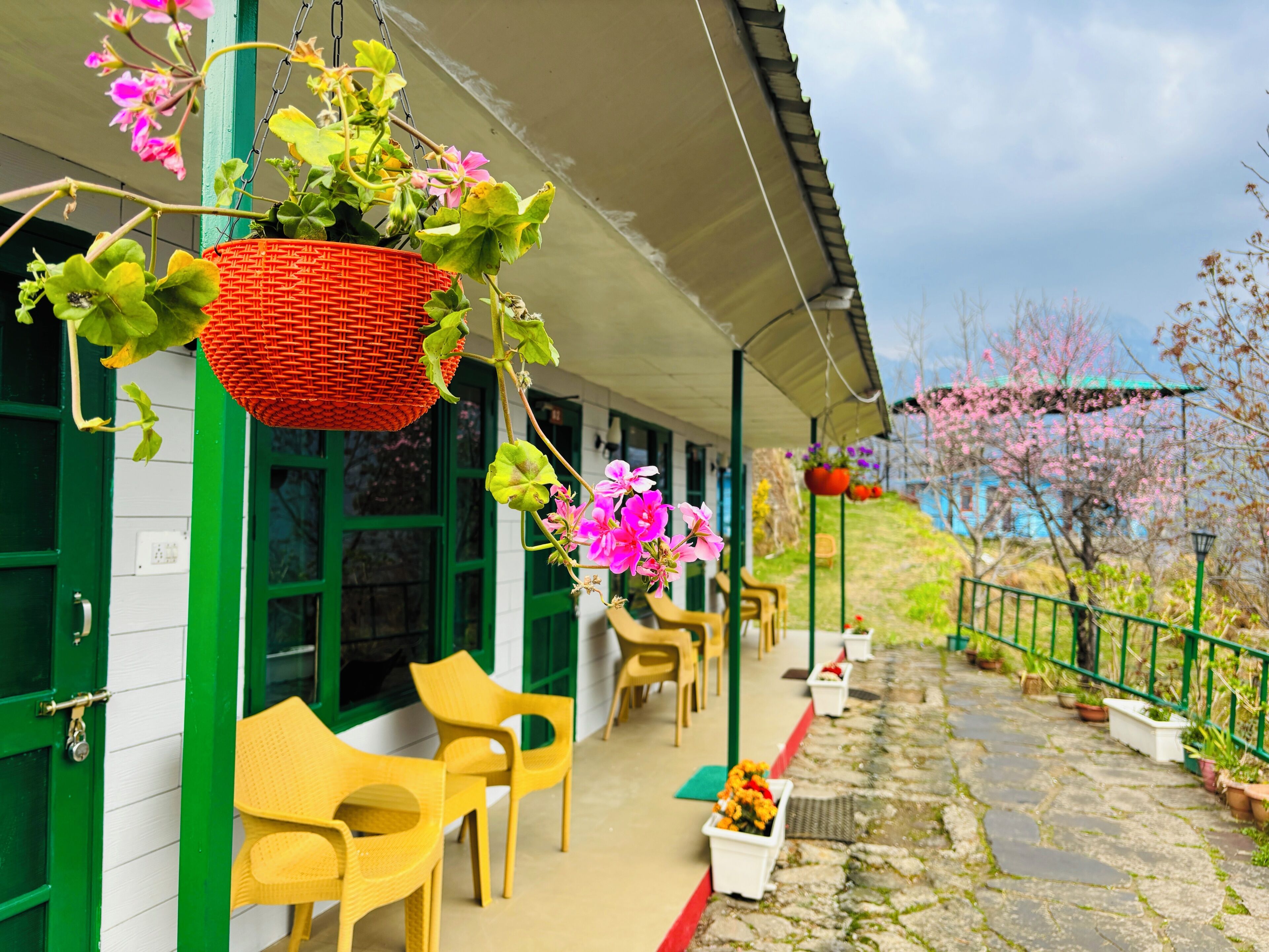 A covered outdoor seating area with chairs and hanging flower baskets.